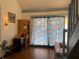a room with a window with a curtain with flowers at APPARTEMENT LOTUS avec PISCINE et à 3 min de la PLAGE Pointe Marin in Sainte-Anne
