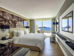 a bedroom with a white bed and a large window at Rixos Premium Dubrovnik in Dubrovnik