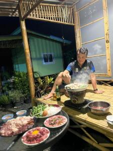 a man sitting at a table with plates of food at พีเจ คิงดอม โฮมสเตย์ in Buriram +3 photos