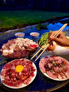 a table topped with plates of food with chopsticks at พีเจ คิงดอม โฮมสเตย์ in Buriram