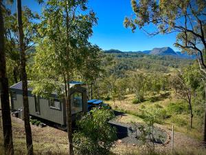 a tiny house in a forest with mountains in the background at Hilltop Haven Darlington in Darlington