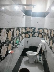 a bathroom with a toilet and flowers on the wall at Rajwaniya home in Jaipur