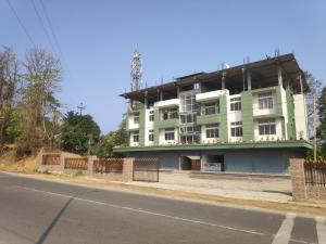 a green and white building on the side of a street at The Siiying in Pāsighāt