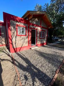 a red house with a door on a gravel driveway at Las Mariposas in Merlo