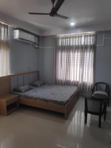 a bedroom with a bed and a chair and a ceiling fan at The Siiying in Pāsighāt