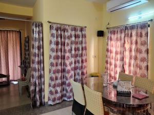 a dining room with curtains and a table and chairs at Surabhi Gardenia 28B-C in Raichak