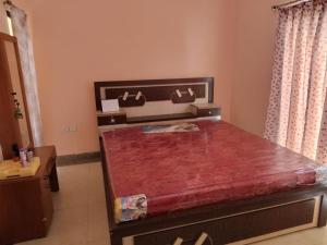 a bed in a room with a red table at Surabhi Gardenia 28B-C in Raichak