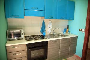 una cucina con armadi blu, lavandino e forno a microonde di Casa Verde Mare a Castel di Tusa