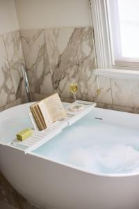 a bath tub with a book and a glass of wine at The Royal Queenscliff in Queenscliff +59 photos