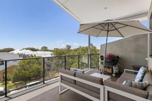 a balcony with a couch and an umbrella at Walk to the Mandurah Foreshore & Marina in Mandurah