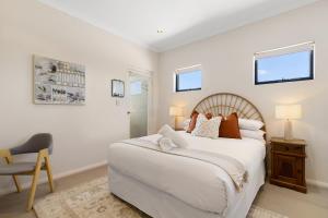 a white bedroom with a large bed and a chair at Walk to the Mandurah Foreshore & Marina in Mandurah