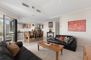 a living room with a black couch and a table at Walk to the Mandurah Foreshore & Marina in Mandurah