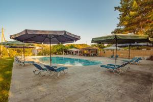 a swimming pool with chairs and umbrellas at Gardenos Hotel in Vitalades