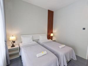 two beds in a hotel room with white sheets at Villa PhyPhy 3 in Gili Trawangan