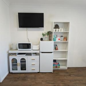a kitchen with a white refrigerator and a microwave at Private Garden Studio - Walk to Beach in Byron Bay