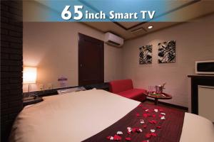 a room with a large bed with a red chair and a red blanket with roses at Hotel Will池袋 Adult Only in Tokyo