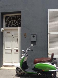 una moto verde estacionada frente a un edificio en Loader Street Cottage, en Ciudad del Cabo