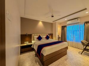 a bedroom with a large bed and a desk at Zip by Spree Hotels Shirdi - Walkable Distance from Sai Baba Temple in Shirdi