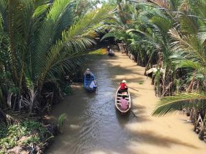 three people in boats in a river between palm trees at H2T Home in Ho Chi Minh City