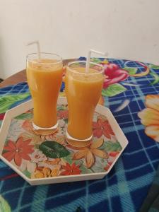 Zwei Gläser Orangensaft stehen auf einem Tablett. in der Unterkunft Binu Home stay in Dikwella