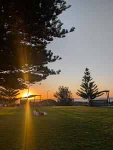 a group of people laying in a field at sunset at 5BR Beachside Home with Pool, Park Access in Perth