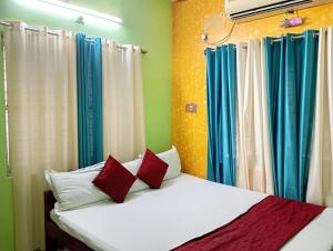 a bedroom with a bed with red and blue curtains at Zeromiles Green Park in Digha