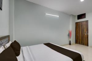 a white bedroom with a bed and a wooden door at Super Hotel O Dadri Main Road Greater Noida in Greater Noida +36 photos