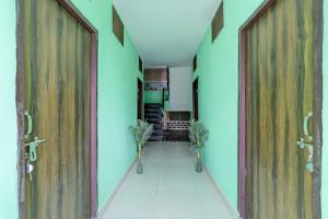 a hallway with two large wooden doors and plants at Super Hotel O Dadri Main Road Greater Noida in Greater Noida