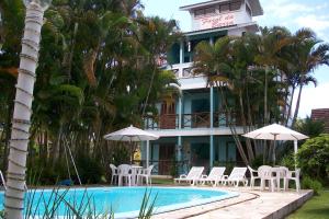 um hotel com uma piscina com cadeiras e guarda-sóis em Pousada Farol da Barra em Florianópolis
