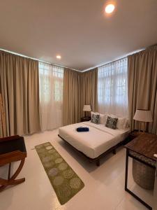 a bedroom with a large white bed with windows at Sunset Beach Retreat & Beach Bistro in Batu Ferringhi