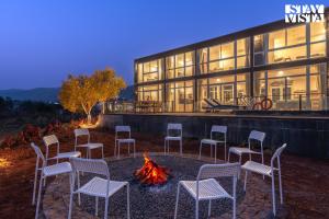 a group of chairs sitting around a fire in front of a building at StayVista at Crimson Bleu - Bonfire & Pet Friendly in Pune