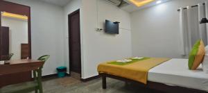 a room with a bed and a desk and a television at Royal Green Residency Chennai Airport in Chennai