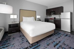 a bedroom with a large white bed and a kitchen at Hawthorn Extended Stay by Wyndham Chambersburg in Chambersburg