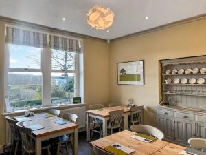 a restaurant with wooden tables and chairs and windows at Bracken Hall House in Baildon