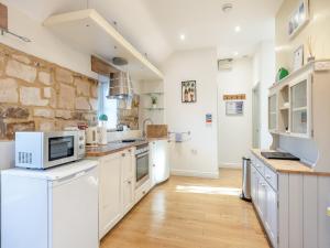 a kitchen with white cabinets and a stone wall at Walnut Cottage - Ukc6632 in Pentney