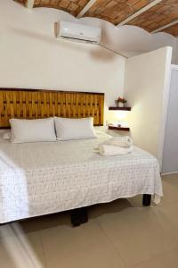 a bedroom with a white bed with a wooden headboard at Casa Baluana vive Sayulita a un paso de todo in Sayulita