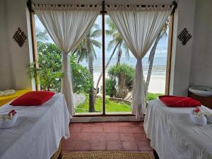 two beds in a room with a view of the ocean at Baobab Sea Lodge in Kilifi