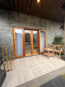 a patio with wooden doors and a table and chairs at Willy Homestay in Uluwatu
