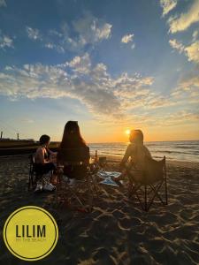 two people sitting in chairs on the beach watching the sunset at Duplex B- Seaside Haven Transient Inn at Caba, La Union in Caba +2 photos