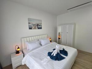 a bedroom with a large white bed with a blue dress on it at Vanesa Serenity Villa 1 in Ban Chong Phli +83 photos