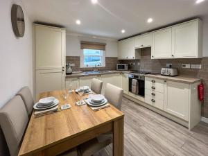 a kitchen with a wooden table with chairs and a dining room at Taigh-Beag - Uk50660 in Wigtown