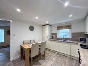 a kitchen and dining room with a wooden table and chairs at Taigh-Beag - Uk50660 in Wigtown