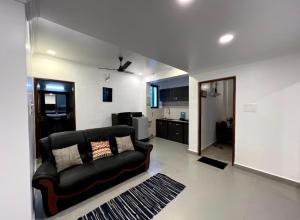 a living room with a black couch and a kitchen at Morden AC 1bhk apartment near Cavelossim beach - Amor in Cavelossim