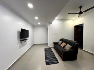 a living room with a couch and a tv on a wall at Morden AC 1bhk apartment near Cavelossim beach - Amor in Cavelossim