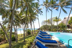 a row of blue lounge chairs next to a swimming pool with palm trees at Baobab Sea Lodge in Kilifi