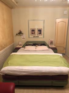 a bedroom with a large bed with green sheets at ホテルNO name in Tōgane