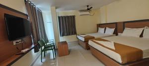 a hotel room with two beds and a flat screen tv at Vijaya Inn in Visakhapatnam