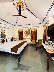 a bedroom with a bed and a desk in a room at Sajjan Bagh Resort in Pushkar