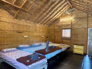 two beds in a room with a roof at Monkey Paradise Hampi in Hampi
