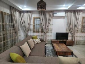a living room with a couch and a tv at Jasmin Prestige Duplex - Hammamet in Hammamet